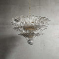 Clear glass Palmette chandelier shown in a wider studio view on a gray wall.