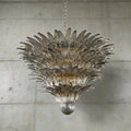 Smoky gray glass Palmette chandelier shown in a large tiered studio view on a gray wall.