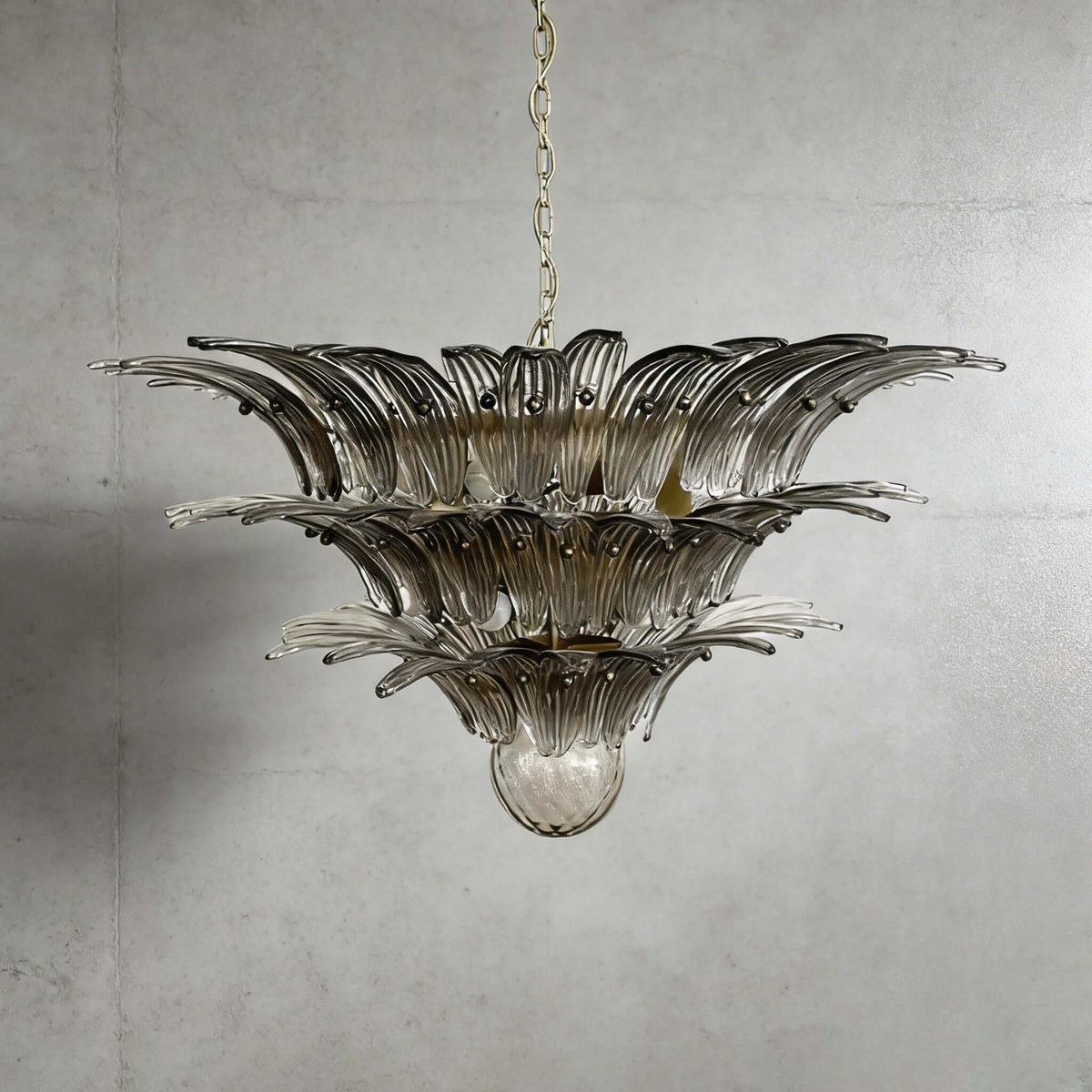 Smoky gray glass Palmette chandelier shown in a wider studio view on a gray wall.